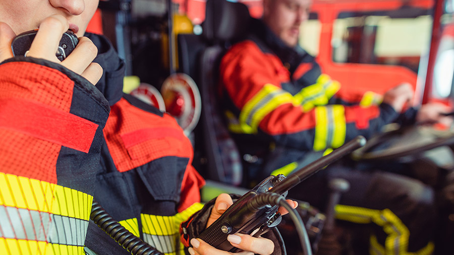 Fire fighter woman on duty using a radio in a fire truck