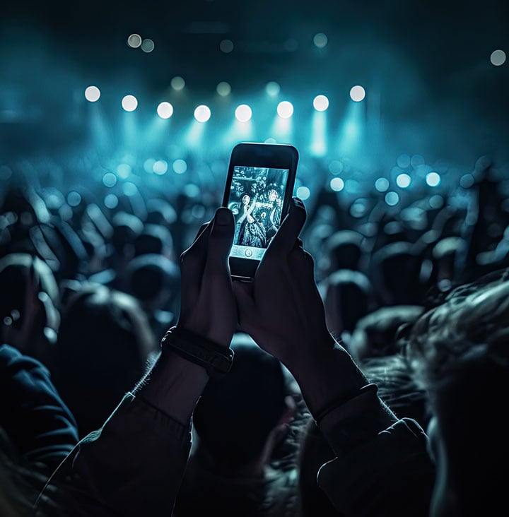 concert with person holding their phone up to record event