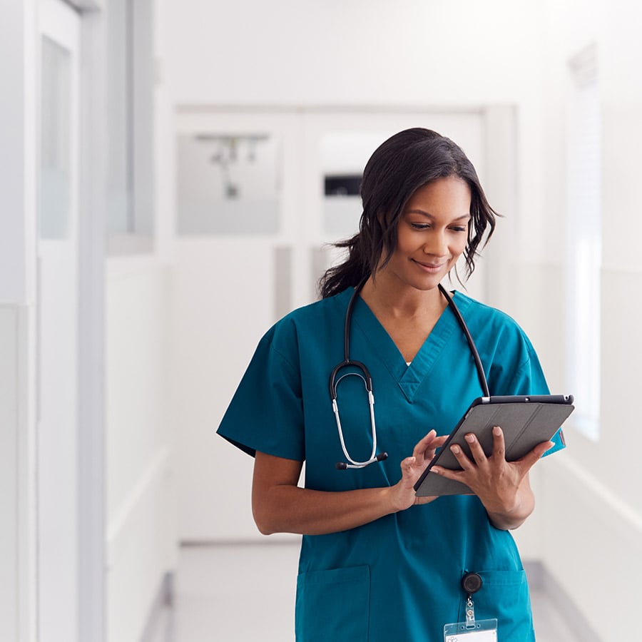 nurse using a tablet in a hospital hallway